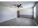 A bedroom with grey carpeting, a black ceiling fan, and natural lighting at 17032 Yellow Pine St, Wimauma, FL 33598