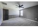 A bedroom with grey carpeting, a black ceiling fan, and natural lighting at 17032 Yellow Pine St, Wimauma, FL 33598