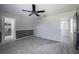 A bedroom with grey carpeting, a black ceiling fan, and natural lighting at 17032 Yellow Pine St, Wimauma, FL 33598