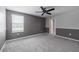 A bedroom with grey carpeting, a black ceiling fan, and natural lighting at 17032 Yellow Pine St, Wimauma, FL 33598