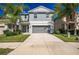 Charming two-story home featuring a gray color scheme, attached two-car garage, and tropical landscaping at 17032 Yellow Pine St, Wimauma, FL 33598