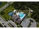 An aerial view of a community pool with sundeck, lounge chairs, tennis courts and clubhouse in a Primary-planned community at 17032 Yellow Pine St, Wimauma, FL 33598