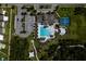 Overhead aerial view of a community pool with lounge chairs, tennis courts, playground, and clubhouse in a Primary-planned community at 17032 Yellow Pine St, Wimauma, FL 33598