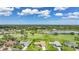 Aerial view of a home on a golf course with a lake in the background and lush greenery at 1915 Pebble Beach Ct, Venice, FL 34293