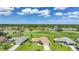 Aerial view of the home featuring a green lawn, garden, and golf course views at 1915 Pebble Beach Ct, Venice, FL 34293