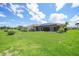 Sprawling backyard with lush green lawn, mature landscaping, and a screened patio at 1915 Pebble Beach Ct, Venice, FL 34293