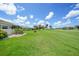 Well-manicured backyard with a lush green lawn and view of the surrounding landscape at 1915 Pebble Beach Ct, Venice, FL 34293