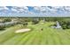 Scenic golf course view with lush green fairways, sand traps, a golf cart, and pond under a blue sky with fluffy clouds at 1915 Pebble Beach Ct, Venice, FL 34293