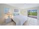 Bright primary bedroom featuring tiled floors, plantation shutters and a view of lush landscaping at 1915 Pebble Beach Ct, Venice, FL 34293