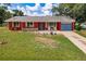 Charming single-story home features a vibrant red exterior, blue garage door, and well-maintained lawn at 20409 Emerald Ave, Port Charlotte, FL 33952