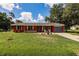 Charming single-story home features a vibrant red exterior, blue garage door, and well-maintained lawn at 20409 Emerald Ave, Port Charlotte, FL 33952