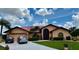 Inviting single-story home featuring a metal roof, arched windows, lush landscaping, and a spacious driveway at 214 Castile Ct, Punta Gorda, FL 33983