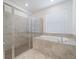 Modern bathroom with a glass-enclosed shower, luxurious tub, and neutral tiled walls at 2161 Gardenia Ave, Port Charlotte, FL 33953