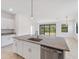 Bright, open kitchen with granite island, stainless dishwasher, and sliding glass doors to backyard at 2161 Gardenia Ave, Port Charlotte, FL 33953