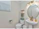 Well-lit half bathroom featuring pedestal sink, decorative shelves, and soft, natural light at 2210 Mauritania Rd, Punta Gorda, FL 33983