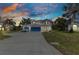 Inviting two-story home featuring blue garage doors and shutters under a colorful evening sky at 2210 Mauritania Rd, Punta Gorda, FL 33983