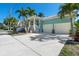 Coastal home featuring a two-car garage, lush landscaping, and vibrant turquoise exterior at 233 Durrance St, Punta Gorda, FL 33950