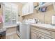 Laundry room featuring front loading washer/dryer, utility sink, storage cabinets, and window with plantation shutters at 233 Durrance St, Punta Gorda, FL 33950