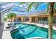 Relaxing screened-in pool area with a water feature and ample seating, surrounded by lush landscaping at 26090 Rampart Blvd, Punta Gorda, FL 33983