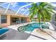 Beautiful screened-in pool area with palm trees, spa and blue lounge chairs at 26090 Rampart Blvd, Punta Gorda, FL 33983