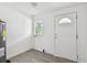 Bright laundry room featuring a water heater, window, white walls, gray flooring, and white exterior door at 2626 E 38Th Ave, Tampa, FL 33610