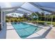 Beautiful screened-in pool with lounge seating, umbrella table and lush landscaping at 3270 Ithaca St, Port Charlotte, FL 33952