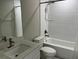 Bathroom features a shower-tub combo with white tile, a granite vanity top and brushed bronze fixtures at 3532 Richardson St, North Port, FL 34288