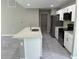 Modern kitchen with white cabinets, stainless steel appliances, island with bar seating, and gray wood-look flooring at 3532 Richardson St, North Port, FL 34288