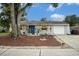 Charming single-story home features a well-manicured lawn, bright shutters and a vibrant blue front door at 3612 Patina Dr, Tampa, FL 33619