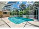 Screened-in pool area featuring a sparkling pool, lush tropical landscaping, and a serene outdoor oasis at 510 Border St, Port Charlotte, FL 33953