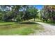 Expansive backyard featuring lush green grass, mature trees, and a dirt road at 6594 Buckboard St, North Port, FL 34291