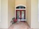 Inviting front entrance with a red double door, stone flooring, and charming bench seating at 6594 Buckboard St, North Port, FL 34291
