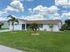 Well-maintained single-story home with a green lawn, palm trees, and tidy landscaping at 724 Hartford Nw Dr, Port Charlotte, FL 33952