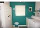 A bright laundry room with washer, dryer, and utility sink features painted teal walls and a window at 724 Hartford Nw Dr, Port Charlotte, FL 33952
