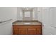 Bathroom with a granite vanity, wooden cabinets, large mirror and tiled walls at 1107 Seneca Rd, Venice, FL 34293