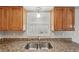 Close-up of a kitchen sink with wooden cabinets and granite countertops under natural light at 1107 Seneca Rd, Venice, FL 34293