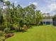 Picturesque backyard featuring mature trees, colorful landscaping, and a storage shed at 12300 El Prado Dr, Punta Gorda, FL 33955
