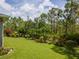 Well-manicured backyard with lush green grass, mature trees, and colorful plants and flowers at 12300 El Prado Dr, Punta Gorda, FL 33955