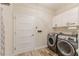 Well-lit laundry room with modern appliances, white cabinets and wood-look tile floors at 12300 El Prado Dr, Punta Gorda, FL 33955