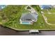 Aerial view featuring backyard with a private pool, dock, and meticulously maintained green lawn along a waterfront canal at 12581 Eisenhower Dr, Port Charlotte, FL 33953