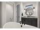Modern bathroom features a freestanding tub, round mirror, and gray cabinets with marble countertop at 12581 Eisenhower Dr, Port Charlotte, FL 33953