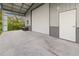 A spacious garage with an open bay door, concrete floor, and high ceilings that can be utilized for storage and projects at 12581 Eisenhower Dr, Port Charlotte, FL 33953