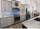 Modern kitchen featuring gray cabinetry, stainless steel appliances, and bright blue backsplash at 12581 Eisenhower Dr, Port Charlotte, FL 33953