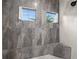 Elegant shower with gray marble-like tile and two windows for natural light at 12581 Eisenhower Dr, Port Charlotte, FL 33953