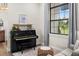 Comfortable sitting room featuring hardwood floors, a black piano, a large window, and a cozy loveseat at 12581 Eisenhower Dr, Port Charlotte, FL 33953