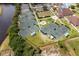 An aerial view shows community tennis courts and a community center with lush landscaping near a body of water at 13136 N Marsh Dr, Port Charlotte, FL 33953