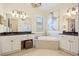 A well-lit bathroom showcases double sinks, a soaking tub, and elegant fixtures and finishes at 13136 N Marsh Dr, Port Charlotte, FL 33953