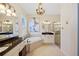 Bright bathroom featuring double vanity sinks, a soaking tub, and a glass-enclosed shower at 13136 N Marsh Dr, Port Charlotte, FL 33953