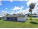 Scenic backyard with manicured grass, bordered by palm trees and showcasing the rear of the property at 1389 Hinton St, Port Charlotte, FL 33952