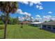 Expansive backyard featuring manicured lawn, mature palm trees, and a clear blue sky at 1389 Hinton St, Port Charlotte, FL 33952
